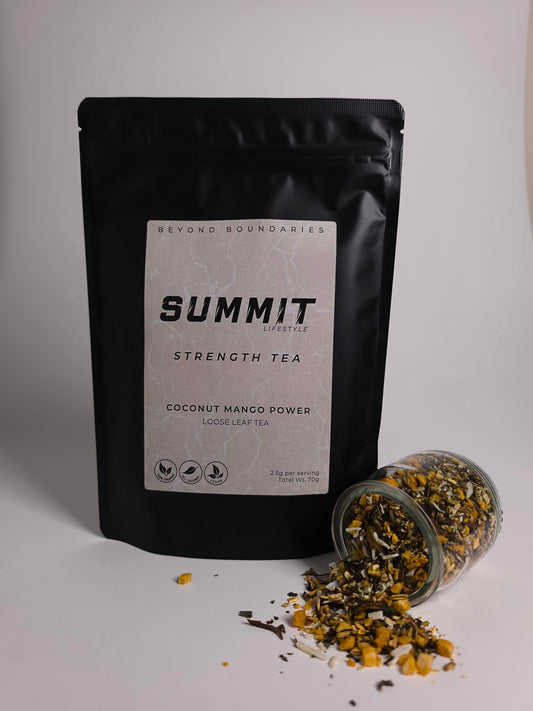 A black stand-up pouch of Beyond Boundaries Summit Strength Tea, Coconut Mango Power flavor, shown next to a clear glass jar tipped over with loose tea spilled out on a light gray background.